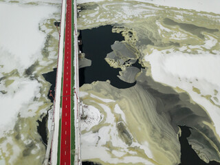 Pedestrian bridge over the Dnieper river in Kiev. Snow patterns on the river. Aerial drone view. Winter snowy morning.