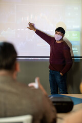 Wall Mural - Young confident business coach pointing at one of several graphs on whiteboard