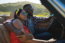 Diverse Couple Driving On Sunny Day In Convertible Car Embracing And Smiling