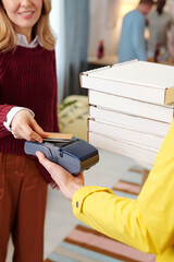 Wall Mural - Young smiling blond female holding credit card over screen of payment machine