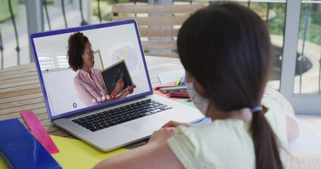 Canvas Print - Caucasian schoolgirl in face mask using laptop on video call with female teacher