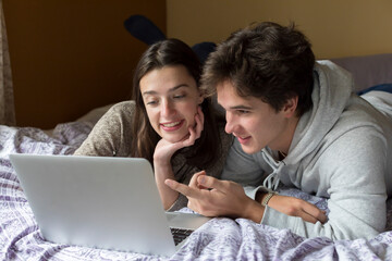 A caucasian male and female college student work on a laptop together