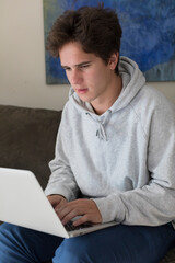 A caucasian male college student works on a laptop