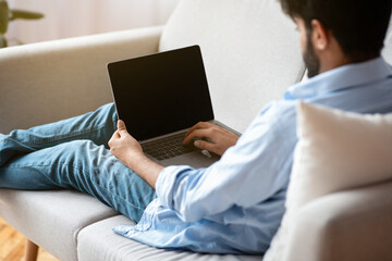 Poster - Unrecognizable Eastern Man Using Laptop Computer With Blank Black Screen At Home