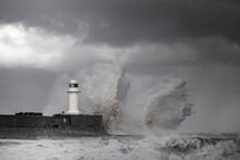 Wintry And Stormy Seas Crashing Over Breakwater With Lighthouse