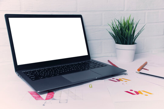 Creative workplace of a Graphic Designer with mockup laptop. Development of a logo for the company. Drawings and sketches on paper in a art studio office.