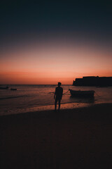 Atardecer en la Playa la Caleta, Cadiz, Andalucia España. Silueta de Persona a contraluz. De fondo se ve el Castillo de Santa Catalina