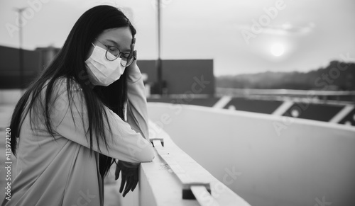 Young Asian woman having headache and illness while wearing mask for protect virus spreading in Covid-19 pandemic outbreak. Woman emotional with black and white tone.