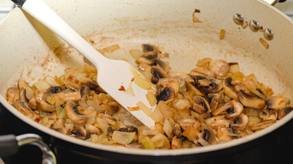 Wall Mural - Chopped white mushrooms and chopped onion close up on frying pan.