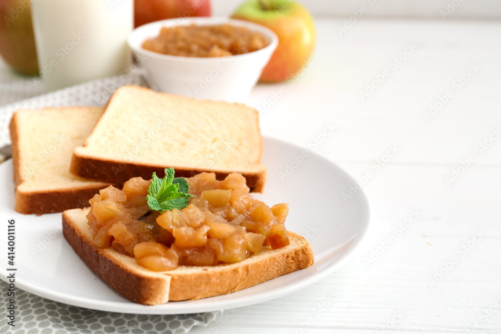 Toast with sweet apple jam in plate on light wooden background
