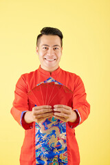 Poster - Portrait of happy young Asian man showing red envelopes with lucky money prepared for Chinese New Year celebration