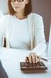 © Iryna - Accountant checking financial statement or counting by calculator income for tax form, hands close-up. Business woman sitting and working with colleague at the desk in office. Audit concept