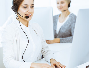 Wall Mural - Call center. Group of diverse operators at work. Beautiful woman in headset communicating with customers of telemarketing service. Business concept