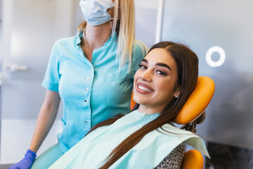 smiling brunette woman being examined by dentist at dental clinic. hands of a doctor holding dental 