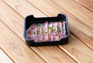 Wall Mural - fresh raw pork belly beef sliced on square plate isolated on wooden background, shabu, hot pot ingredients