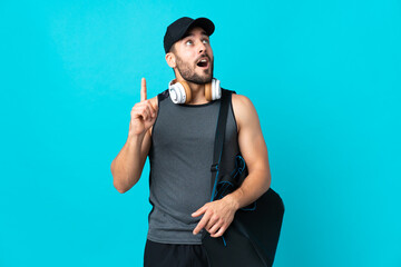 Young sport man with sport bag isolated on blue background thinking an idea pointing the finger up