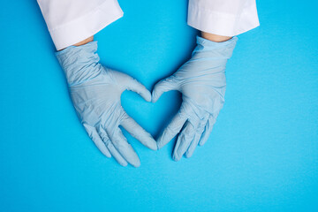 Wall Mural - two female hands in blue latex sterile medical gloves shows a gesture of the heart on a blue background