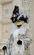 Mask in  in traditional Venetian costume perfectly compatible with palazzo wall at background at traditional Carnival in Vemice, Italy. 