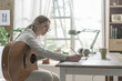 © StockPhotoPro - Woman playing guitar and composing music