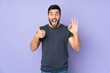 © luismolinero - Caucasian handsome man showing ok sign and thumb up gesture over isolated purple background