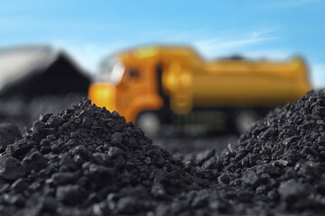 Piles of coal and blurred yellow truck on background, closeup