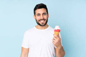 Wall Mural - Caucasian man with a cornet ice cream isolated on blue background smiling a lot