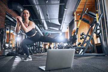 Joyful female instructor doing suspension workout online