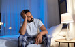 © Syda Productions - sleeping problem, bedtime and insomnia concept - stressed indian man sitting on bed at night at home