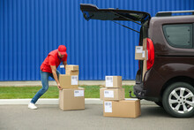 Courier Loading Packages In Car Trunk Outdoors