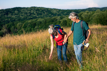 Wall Mural - Active senior couple with backpacks hiking in nature.