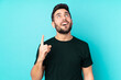 © luismolinero - Caucasian handsome man isolated on blue background pointing up and surprised