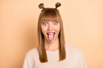 Wall Mural - Photo portrait of childish crazy girl showing tongue in casual outfit isolated on pastel beige color background