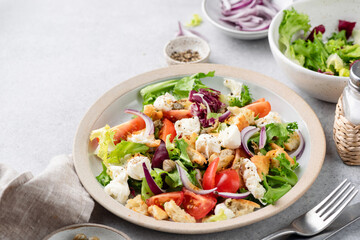 Wall Mural - Healthy salad with lettuce, croutons, tomatoes and mozzarella cheese on a plate. Delicious low calorie vegetarian salad served on a plate