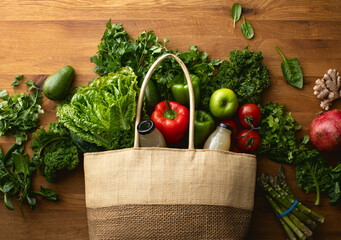 A textile shopping bag full of fresh green vegetables from the farmers market lying on a kitchen table