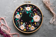 Floral embroidery on a dark convoy and a skein of thread on a gray concrete background 