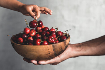 Wall Mural - Wooden bowl with fresh juicy berries. Cherries in hands. Organic eco product, farm.