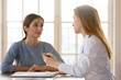 © fizkes - Happy young woman listening to female general practitioner at checkup meeting in clinic office. Professional surgeon gynecologist therapist doctor giving healthcare medical consultation to patient.