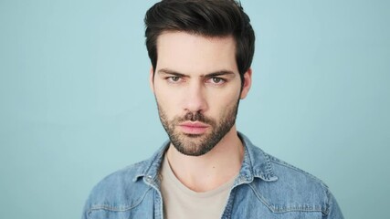 an angry young man is screaming while looking to the camera standing isolated over blue background i