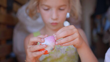 A little girl unfolds and eats a chocolate egg with toys.