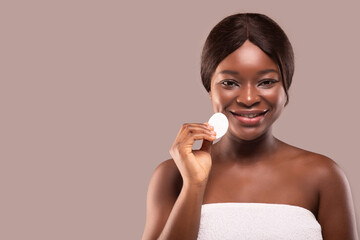 Wall Mural - Portrait of happy black woman holding cotton pad, cleansing face