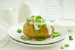 Baked potatoes with cheese, served with sour cream and onions. Selective focus