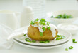 Baked potatoes with cheese, served with sour cream and onions. Selective focus