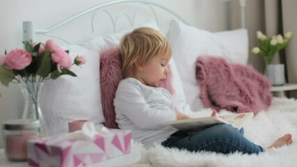 Wall Mural - Cute child, lying in bed, reading book at home