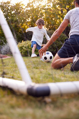 Father With Son Having Fun In Park Or Garden Playing Soccer Together