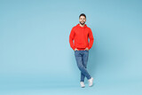 Fototapeta  - Full length young caucasian smiling bearded handsome student man 20s wear casual red orange hoodie standing akimbo arms on waist isolated on blue background studio portrait People lifestyle concept