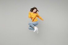 Full Length Of Young Excited Overjoyed Happy Lucky Positive Attractive Woman 20s Wearing Knitted Yellow Sweater Do Winner Gesture Clench Fist Jumping High Isolated On Grey Background Studio Portrait..