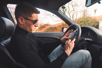 Young caucasian man inside a car using a smartphone