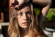 © Dana Keli - close up portrait of young beautiful blonde woman with long wavy hair and blue eyes in harsh sunlight outdoor