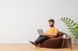 © Foxstudio - Beard cartoon character man seat on brown bean bag use laptop at simple cozy interior with white wall wooden floor. Work at home concept.