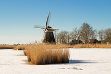 A Landscape Of Frozen Ice With A Windmill In The Background / Een Landschap Of  Bevroren Ijs Met Op De Achtergrond Een Windmolen